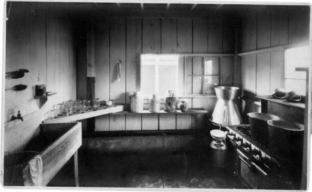 A black and white photo of a kitchen with a sink and stove