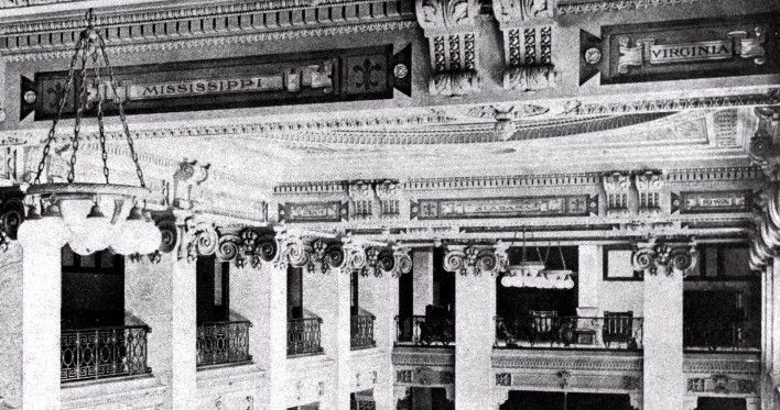 A black and white photo of a building with a chandelier hanging from the ceiling.