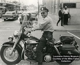 A black and white photo of a police officer riding a motorcycle