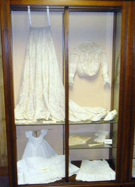 A display case with a white dress and a white shirt