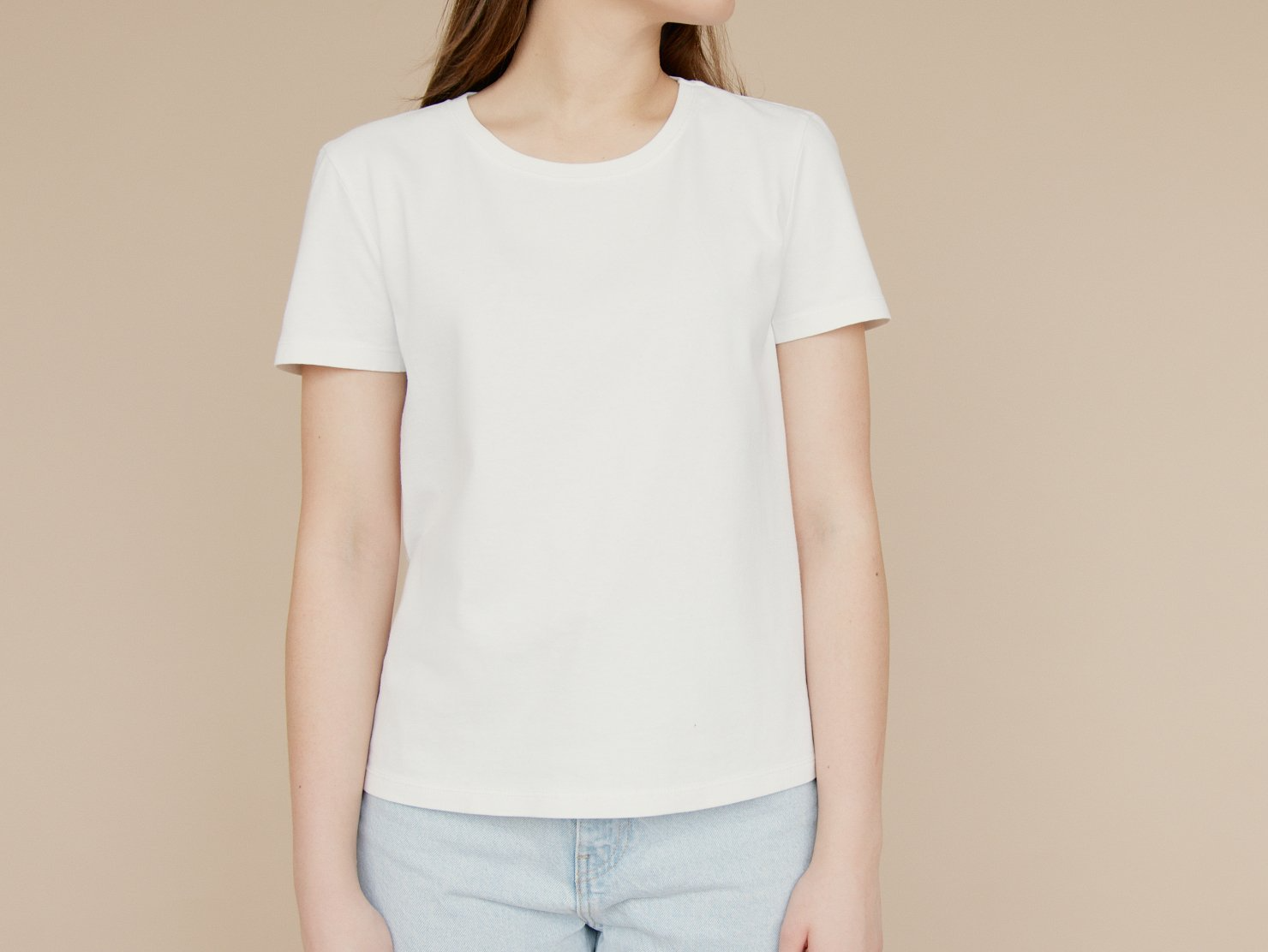 A woman is wearing a white t-shirt and blue jeans.