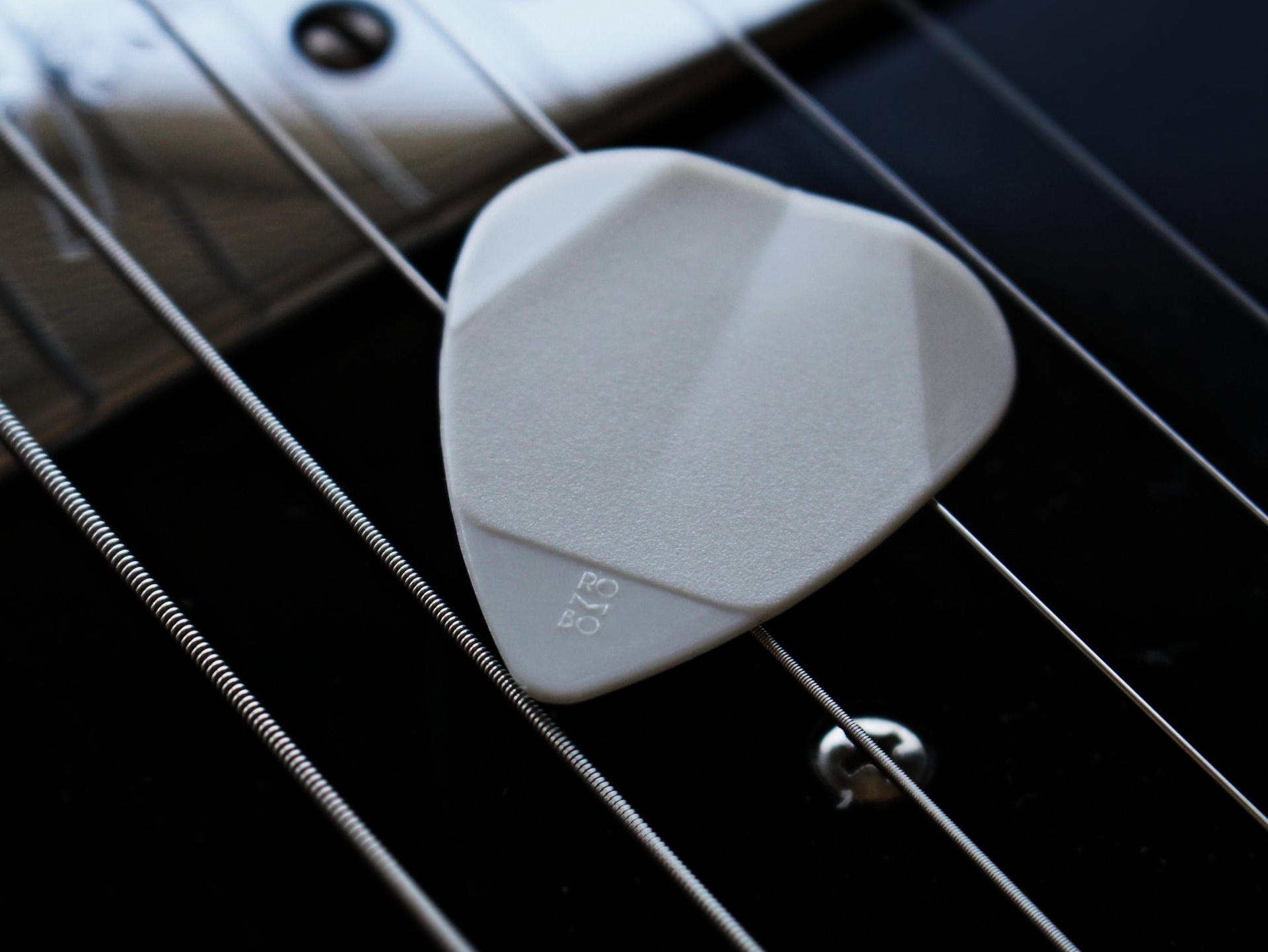 A white guitar pick with the number 13 on it