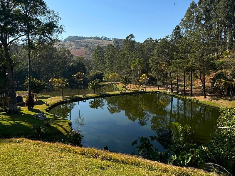 Resort com piscina, edifícios com telhados laranja, palmeiras e um lago sob um céu azul.