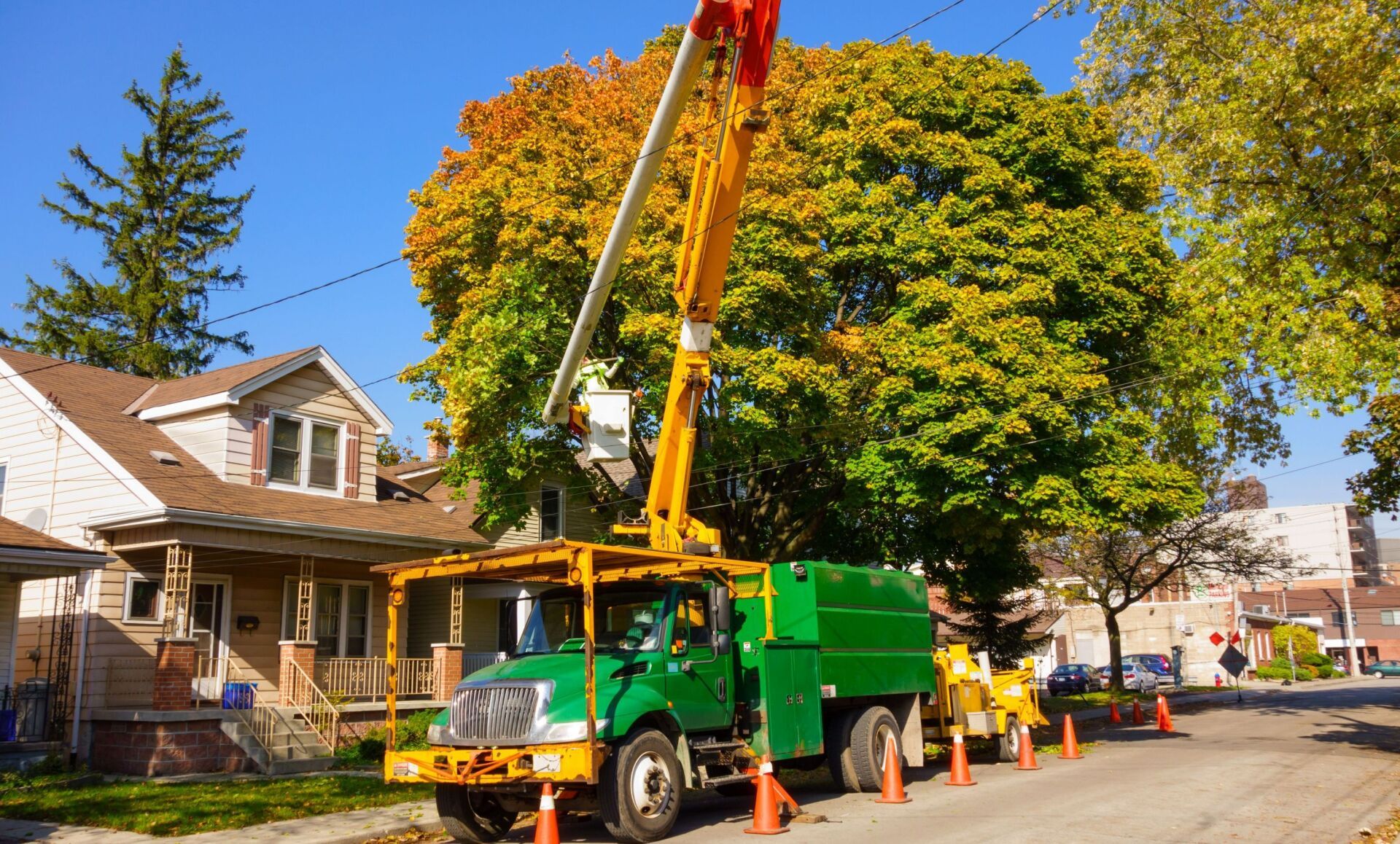 A green truck is parked on the side of the road next to a house.