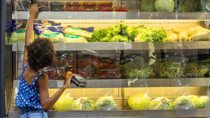 A woman is shopping for vegetables in a grocery store.