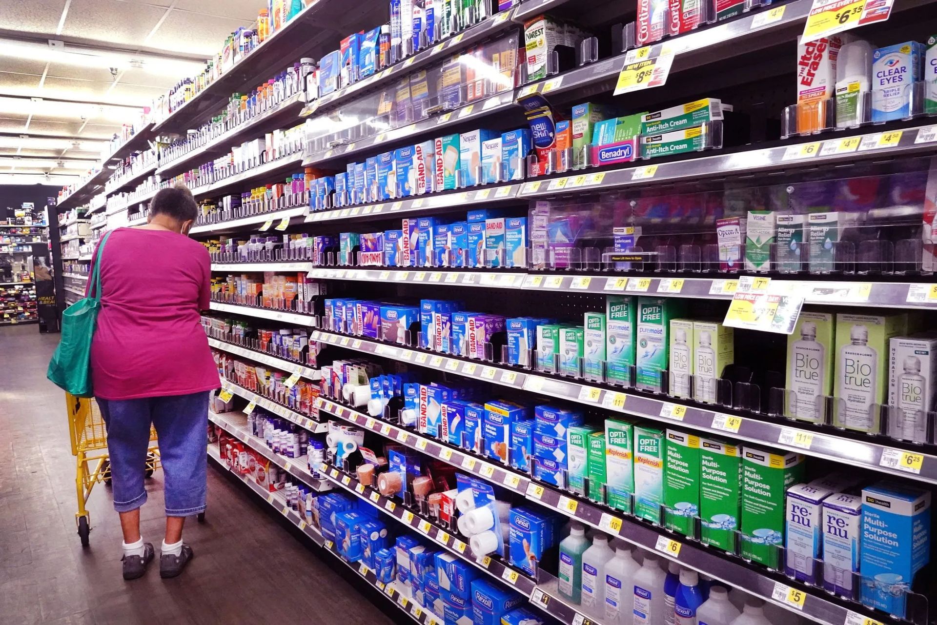 A woman in a pink shirt is shopping in a grocery store.