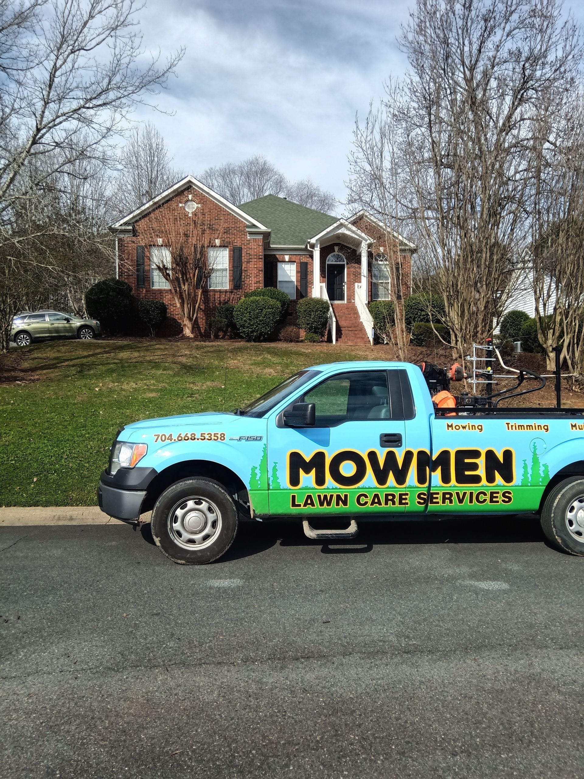 a blue lawn mower truck is parked in front of a house .