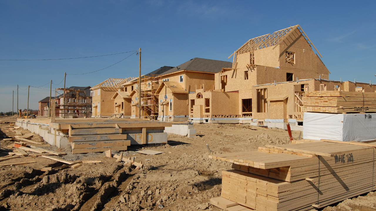 Partially built houses at a construction site under a clear blue sky