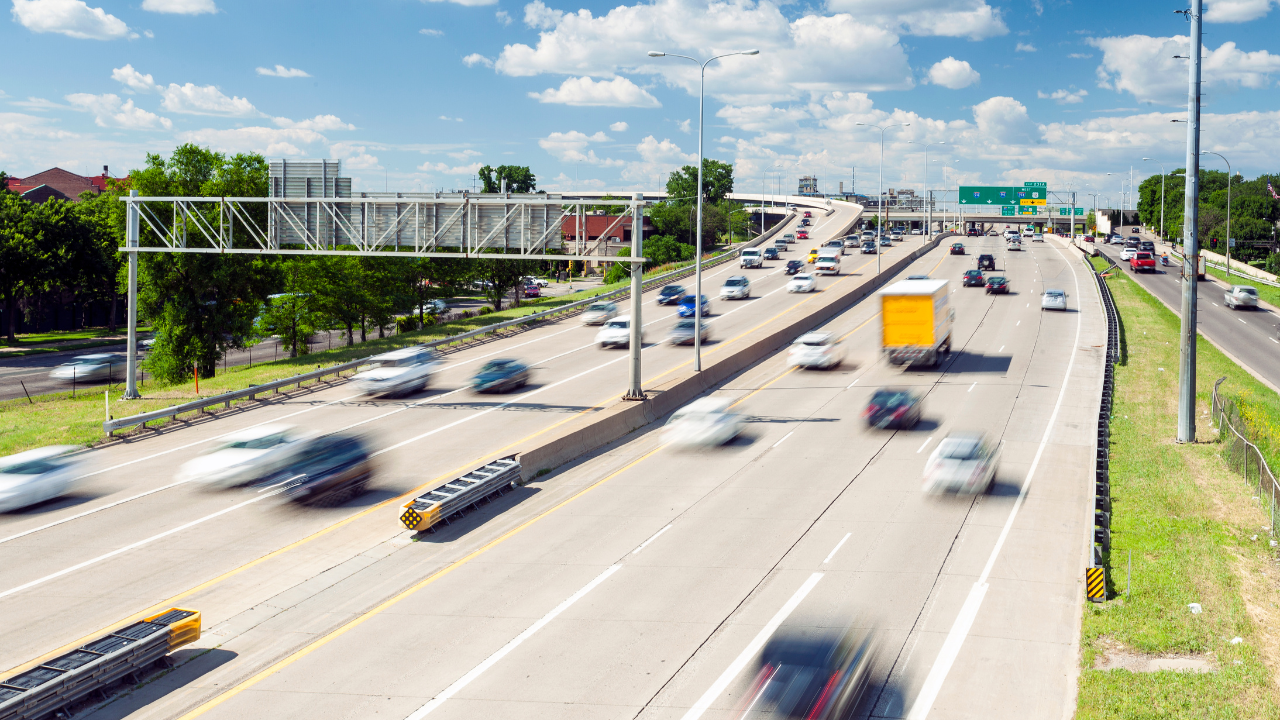 Multi-lane highway with moving cars and trucks under a partly cloudy sky