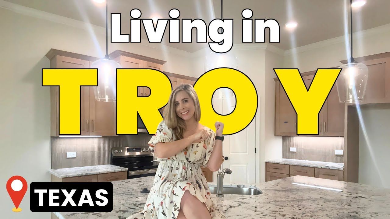 A woman is standing in a kitchen with the words `` living in troy '' written on it.