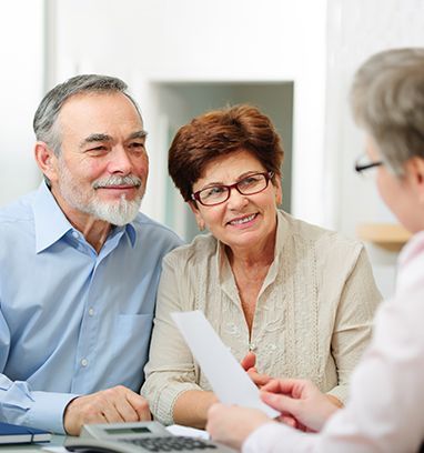 Smiling couple meeting with a financial advisor, looking at documents.