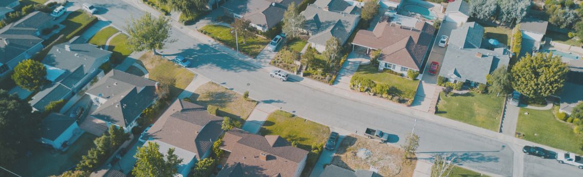 Aerial view of a residential neighborhood with houses, streets, and green lawns.