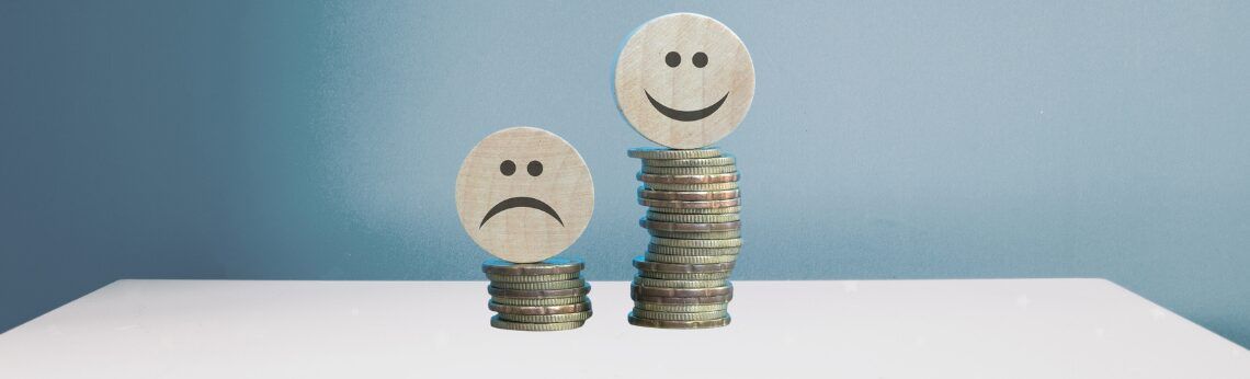 Stacks of coins, one sad and one happy face representing financial status.