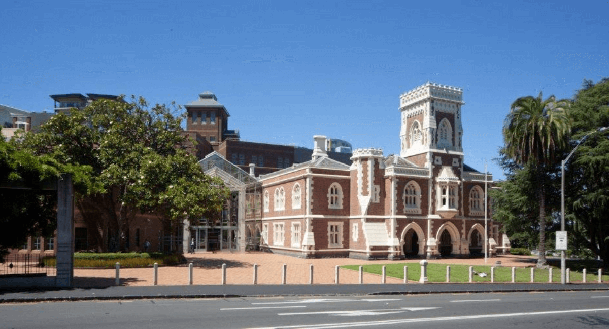 Brown and white brick building with tower, under blue sky.