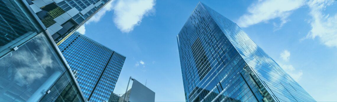 Skyscrapers reaching towards a blue sky with fluffy clouds.