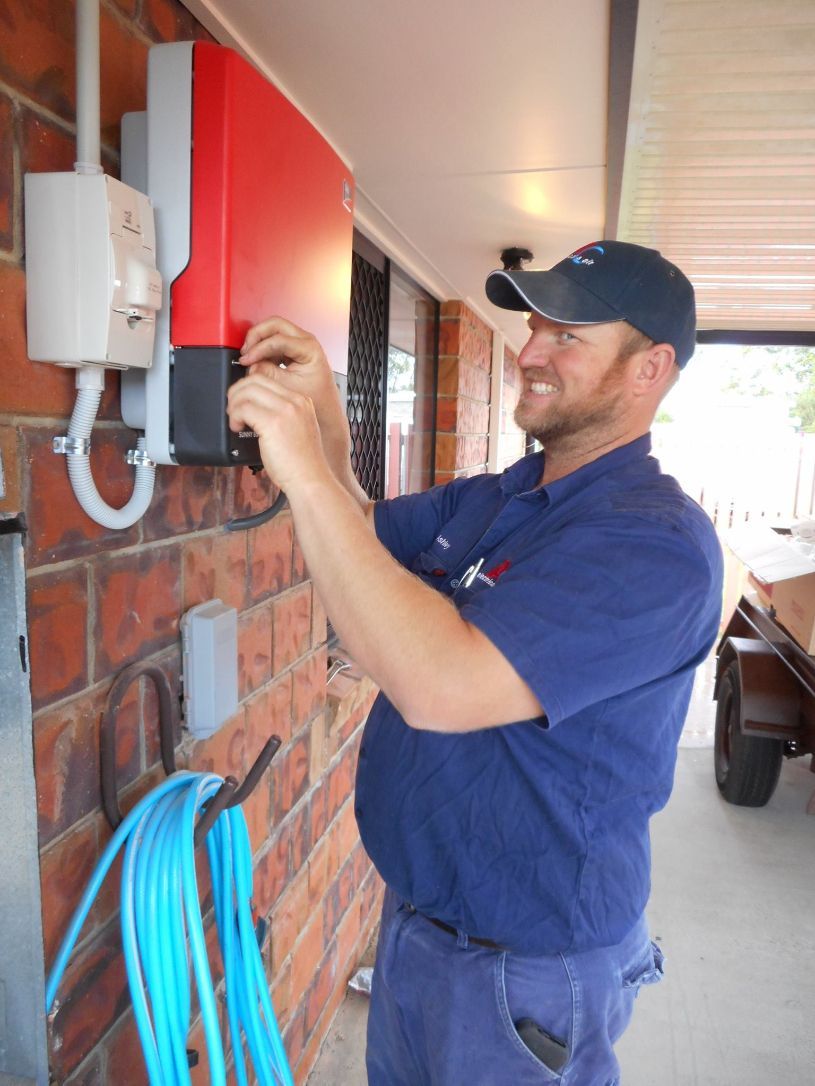 A Man in A Blue Shirt Is Working on A Solar Panel — AC Electrical & Air In Bundaberg Central, QLD