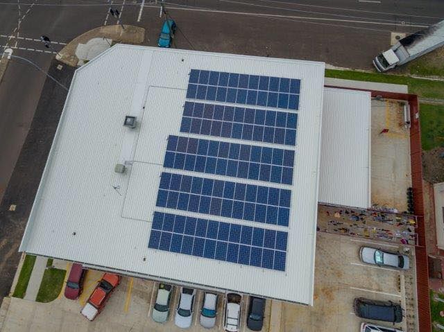 A man is sitting on the roof of a building looking at a laptop. — AC Electrical & Air In Bundaberg Central, QLD