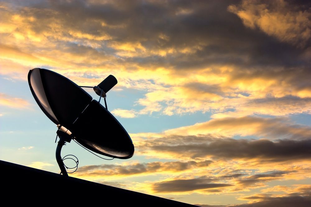 A satellite dish is sitting on top of a roof at sunset — AC Electrical & Air In Bundaberg Central, QLD