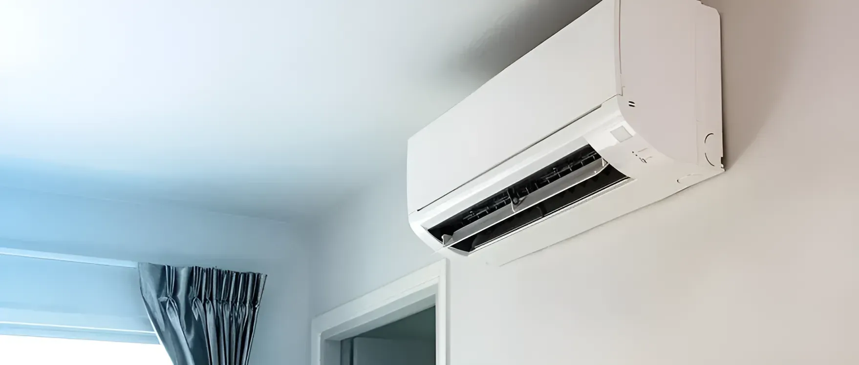 A White Air Conditioner Is Hanging on A White Wall in A Room — AC Electrical & Air In Bundaberg Central, QLD