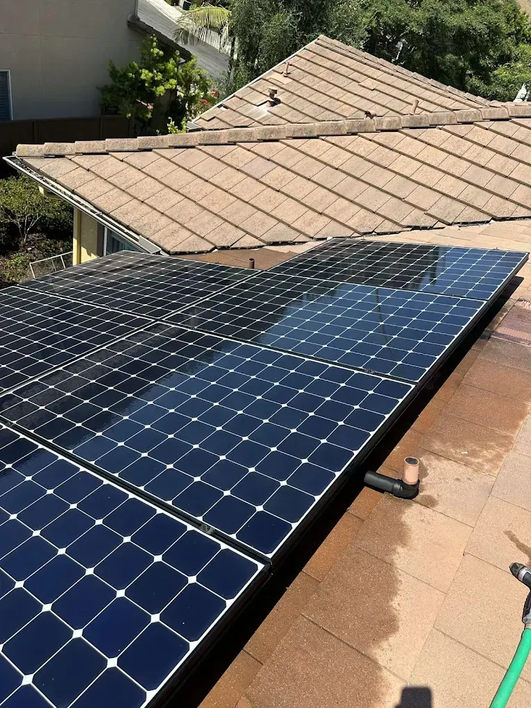 Solar panels installed on a brown tile roof, reflecting the sky.