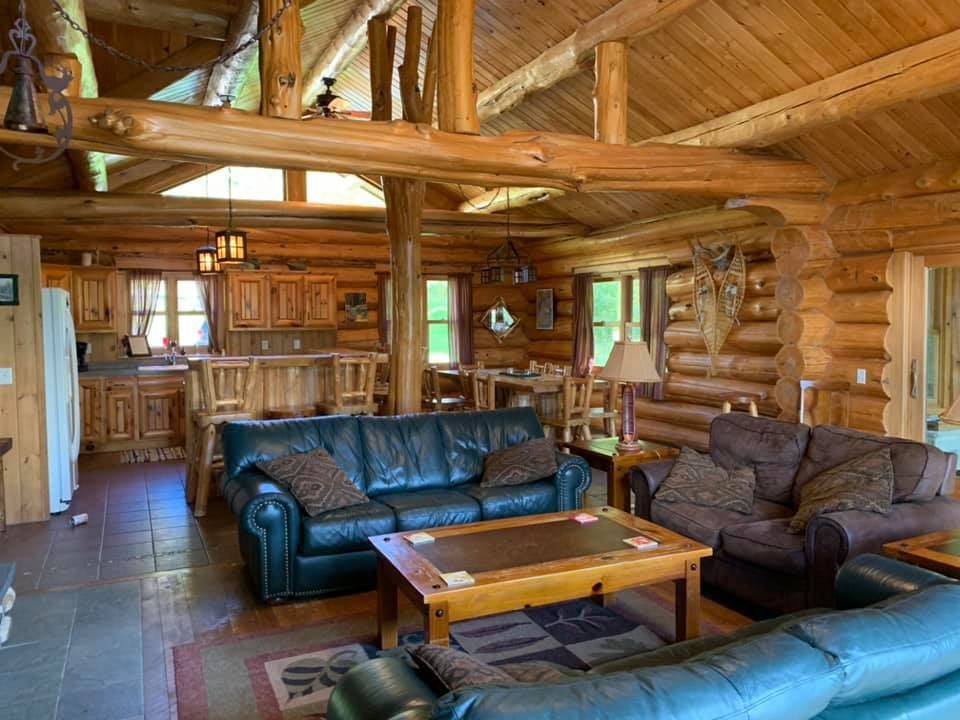 A living room in a log cabin with a couch , chairs and a coffee table.