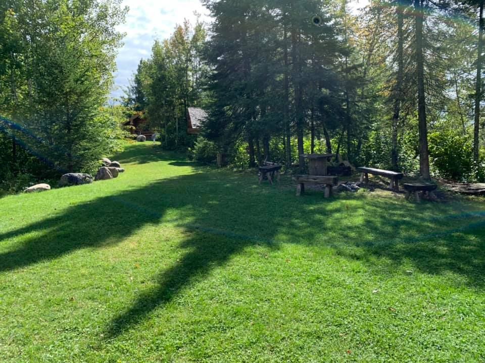 A lush green field with a picnic table and chairs in the middle of it.