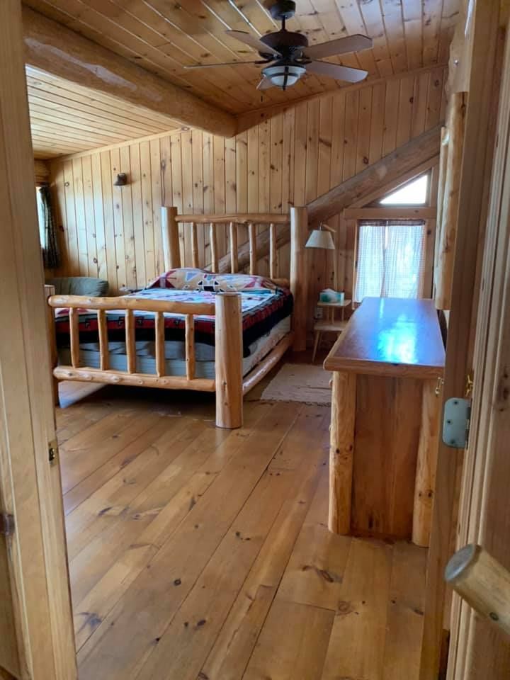 A bedroom in a log cabin with a bed and a ceiling fan.