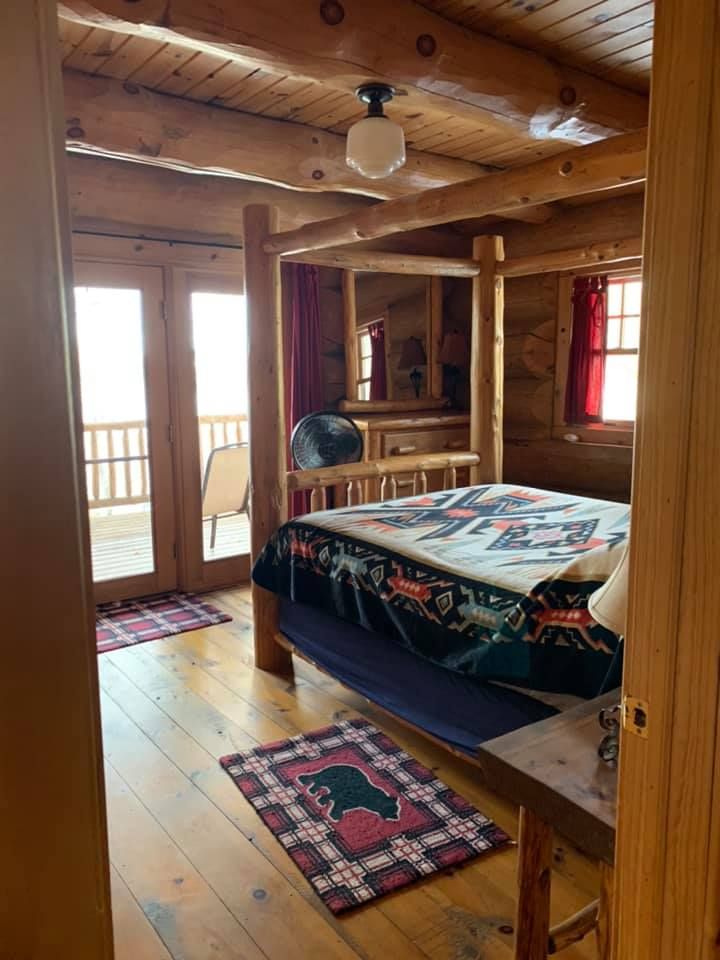 A bedroom in a log cabin with a four poster bed.