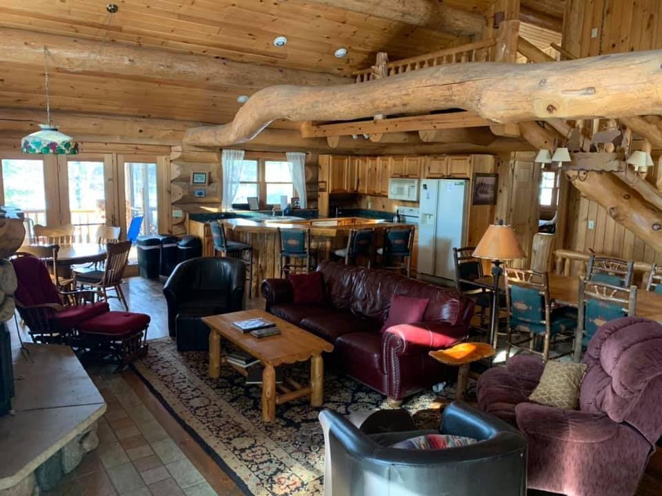 A living room in a log cabin with a couch and chairs