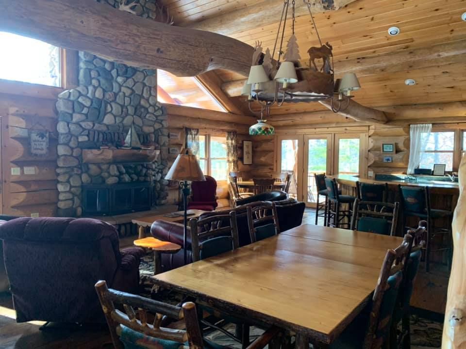 A log cabin living room with a table and chairs and a fireplace.