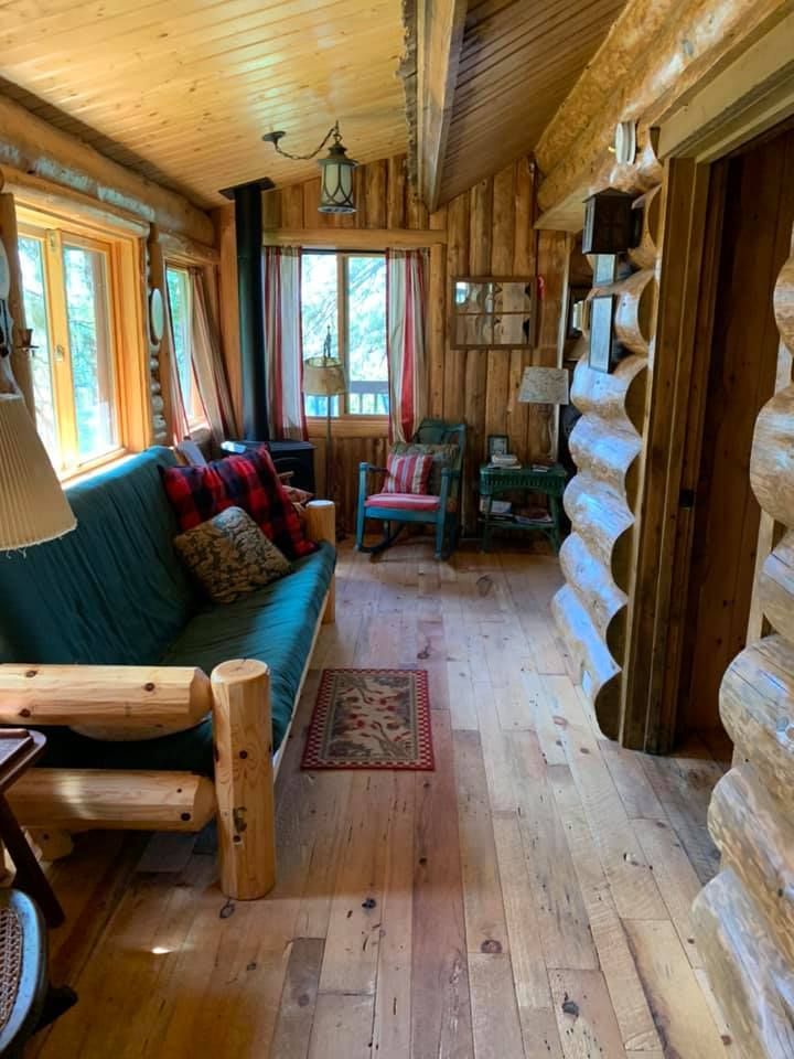 A living room in a log cabin with a couch and chairs.