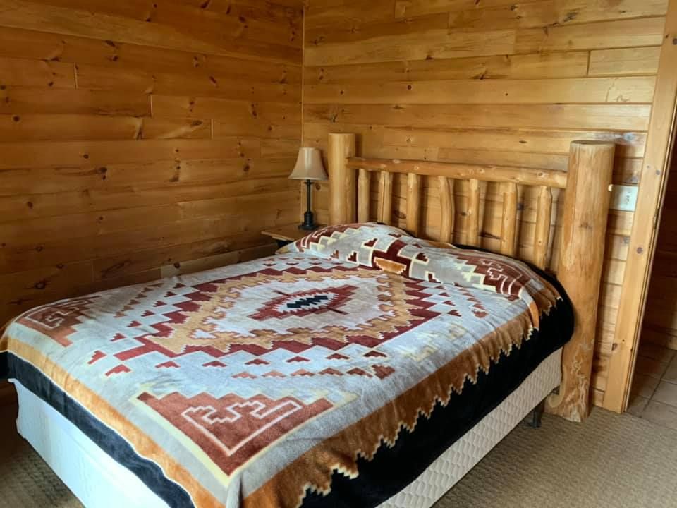 A bed with a blanket on it in a wooden room.