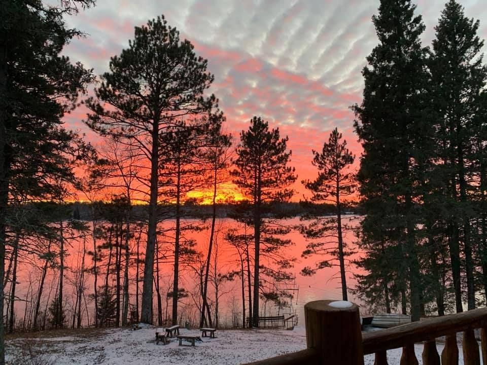 A sunset over a lake with trees in the foreground
