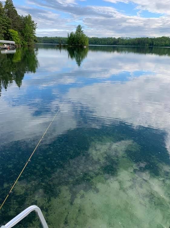 A boat is floating on top of a lake with trees in the background.