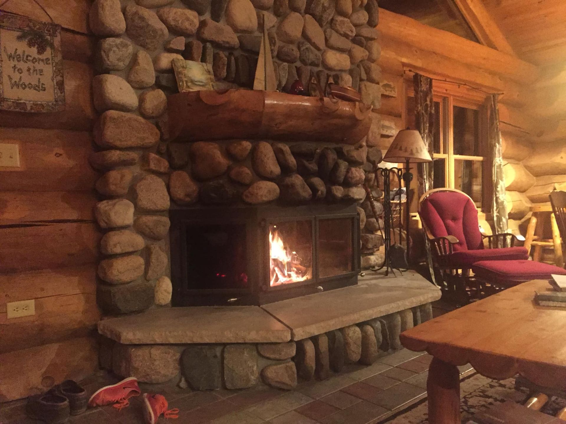 A living room with a fireplace and a sign that says welcome to the woods