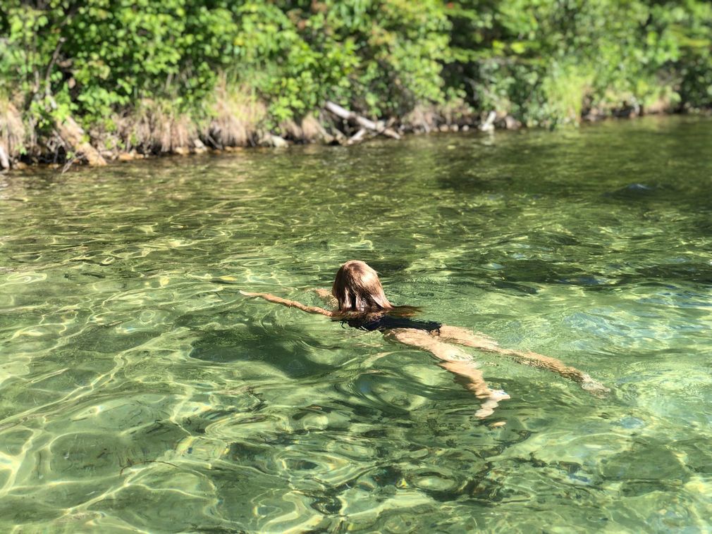 A woman is floating on her back in a lake.