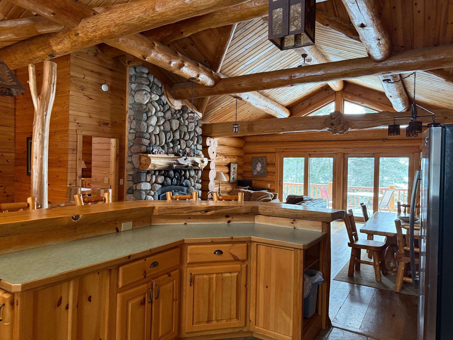 A kitchen in a log cabin with wooden cabinets and a fireplace.