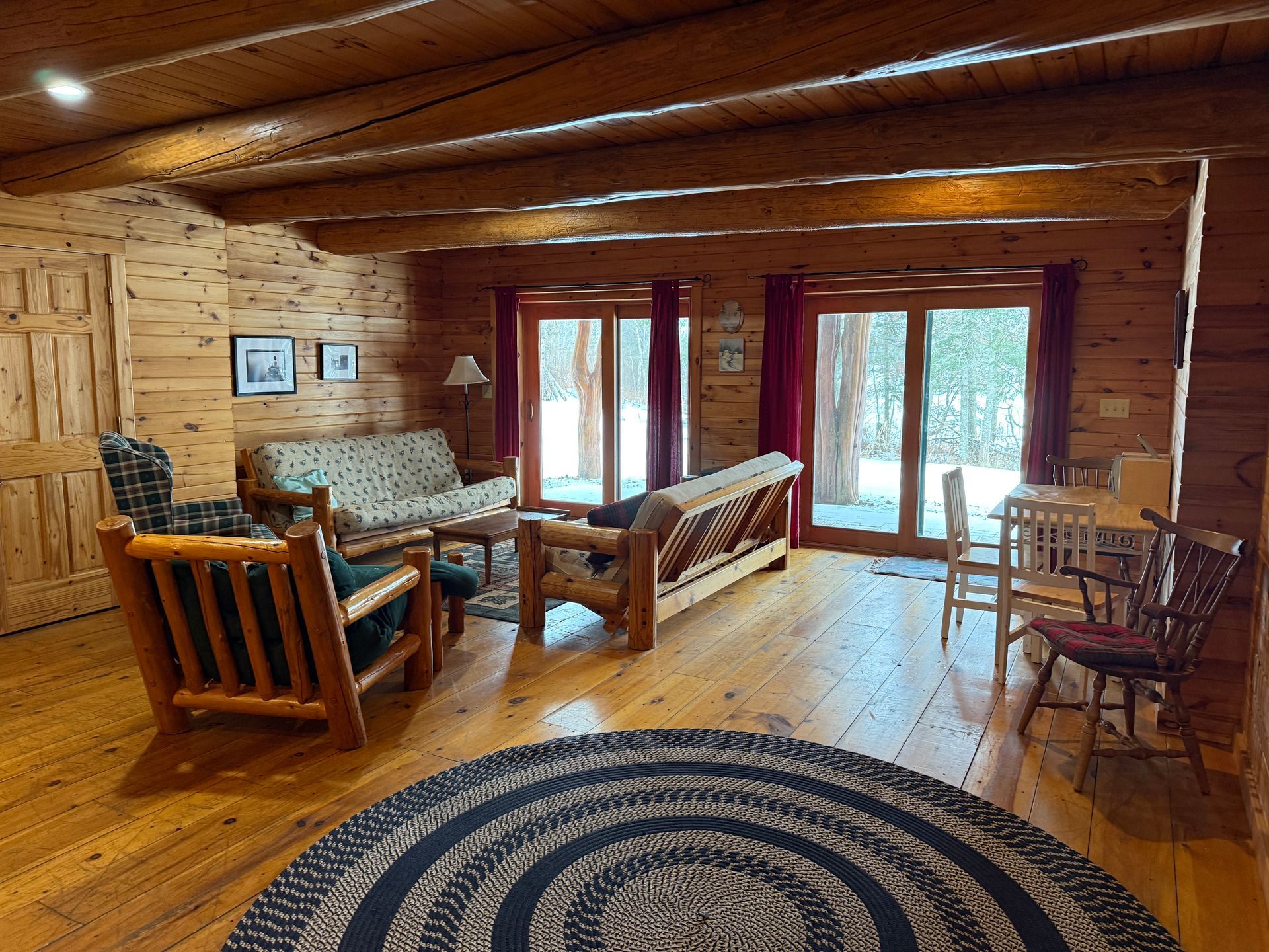 A living room in a log cabin with a couch , chairs , and a rug.