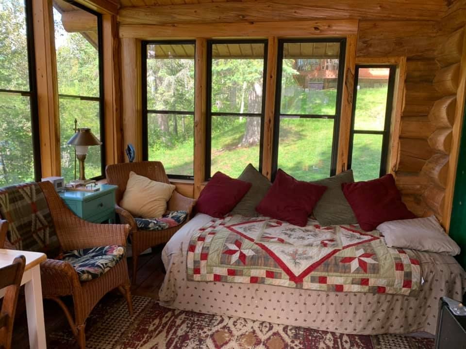 A living room in a log cabin with a couch and chairs