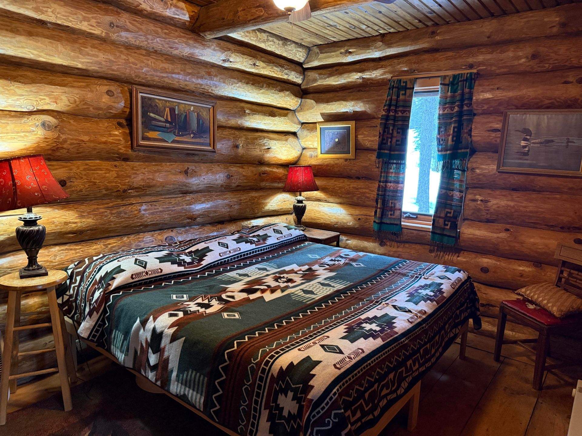 A bedroom in a log cabin with a bed and two lamps.