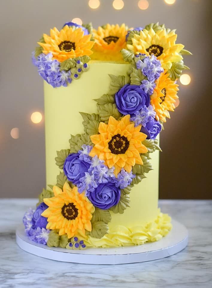 A yellow cake with purple flowers on it is sitting on a table.