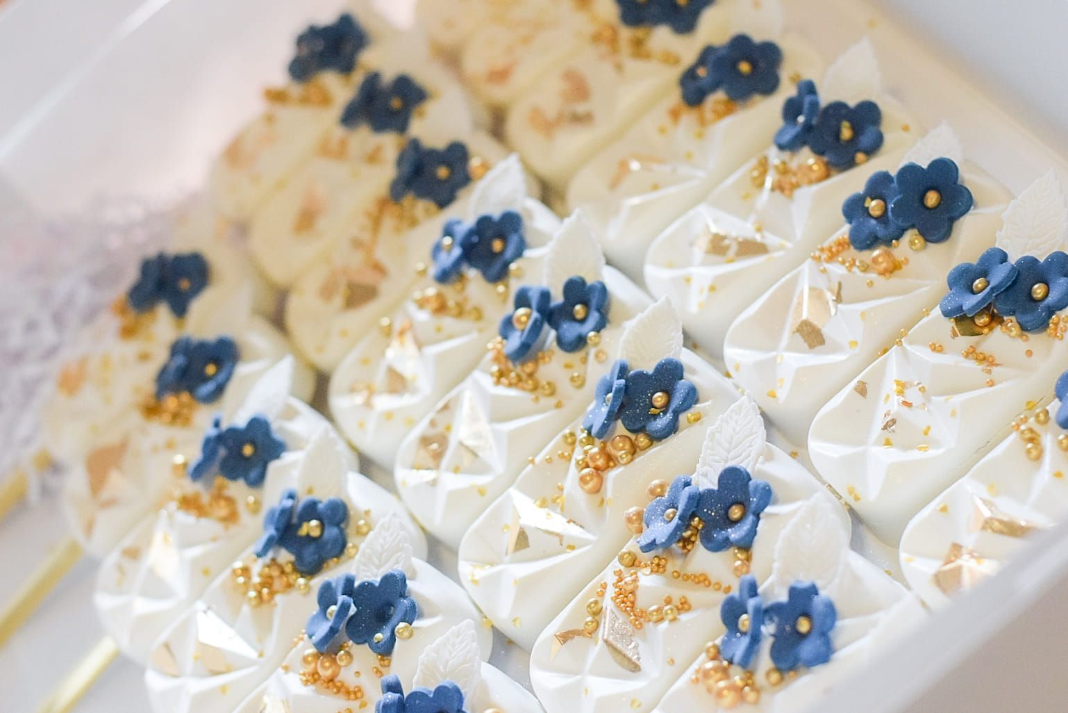 A close up of a white plate topped with white frosting and blue flowers.