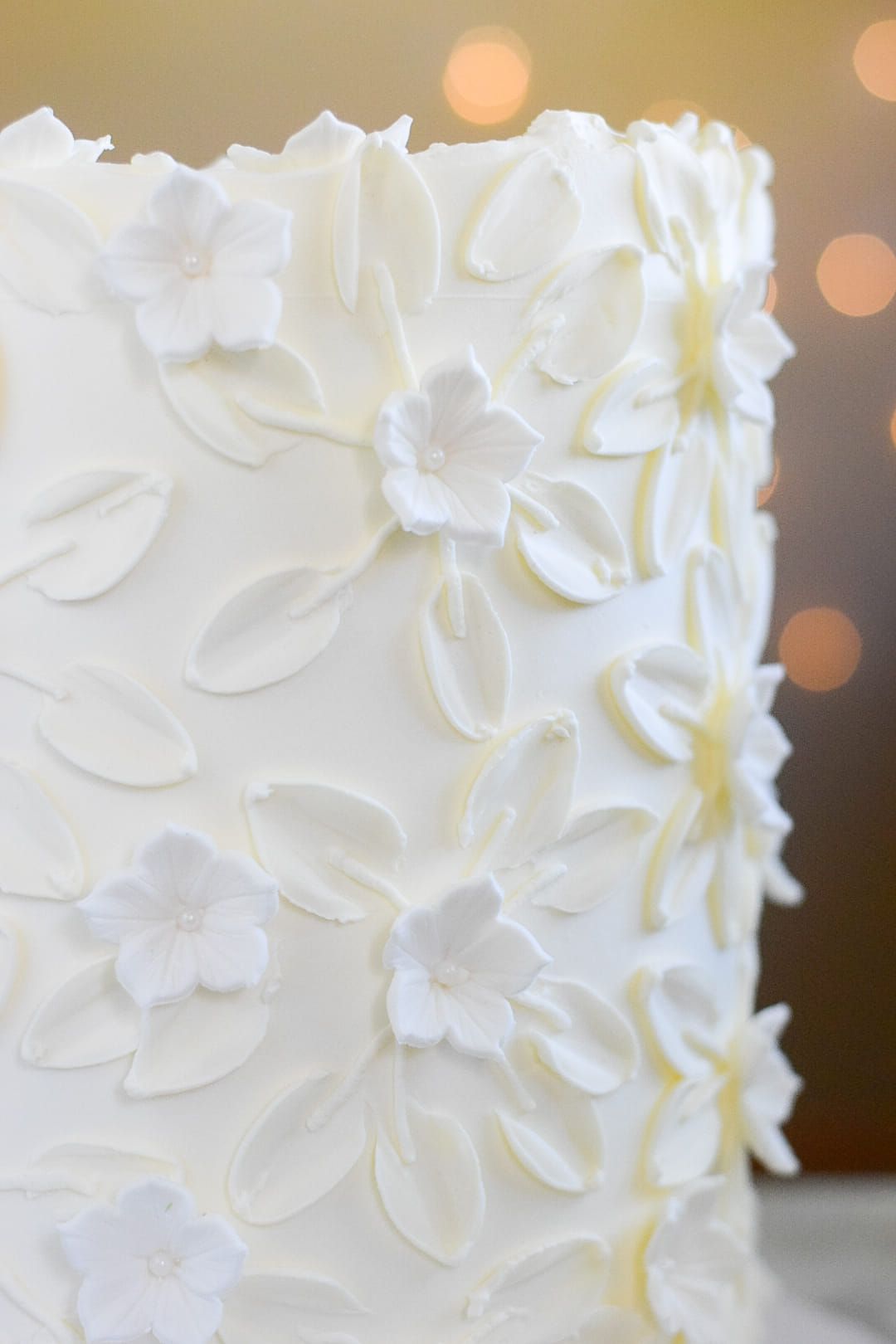 A close up of a white cake with white flowers on it.