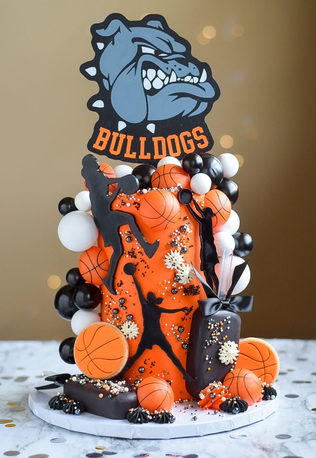 A cake decorated with basketballs and a bulldogs logo is sitting on a table.