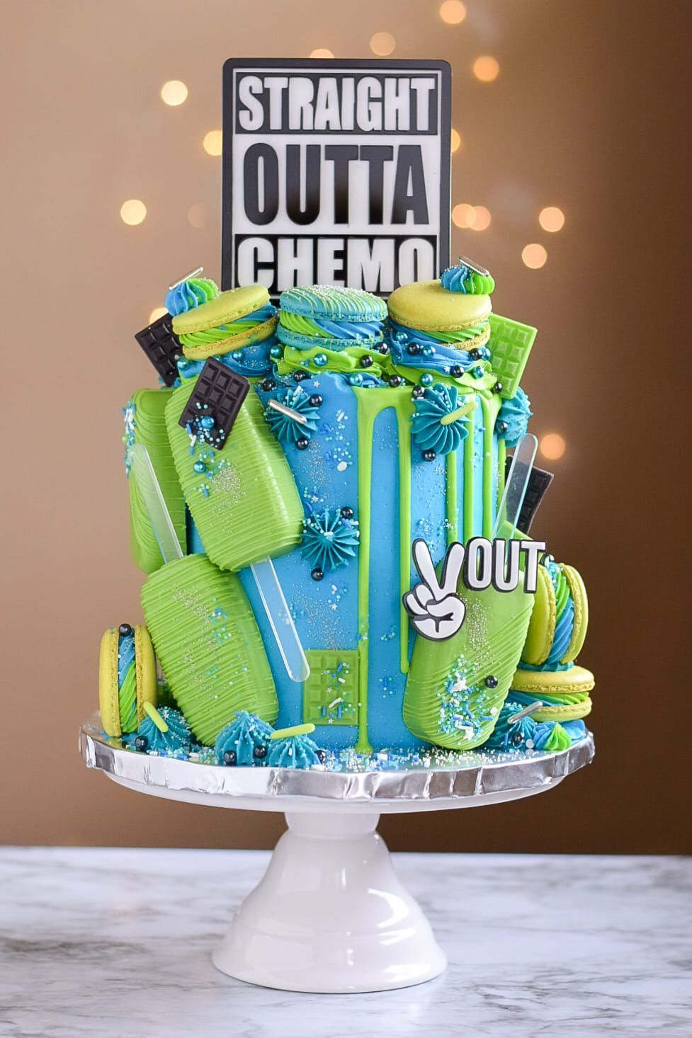 A blue and green cake with a sign that says straight outta chemo