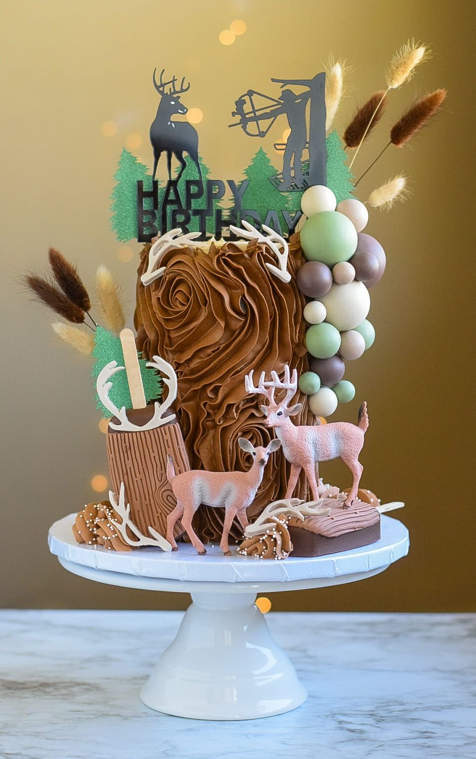 A cake with deer on it is on a cake stand on a table.
