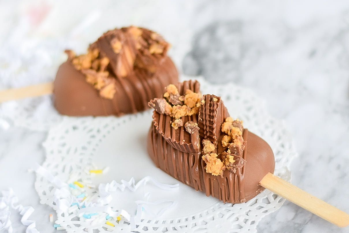 Two chocolate ice cream bars on a white plate on a table.