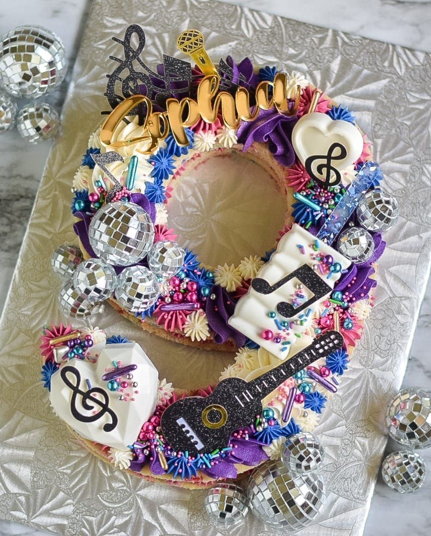 A number cake with a guitar , music notes , and disco balls on it.