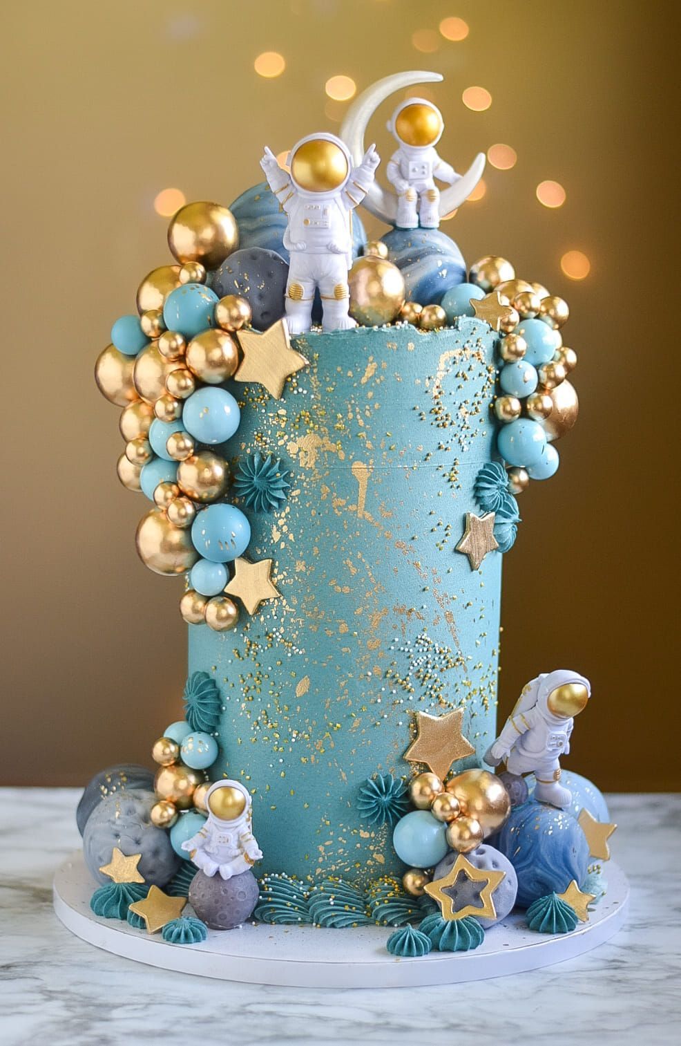 A blue and gold cake with astronauts on top of it.