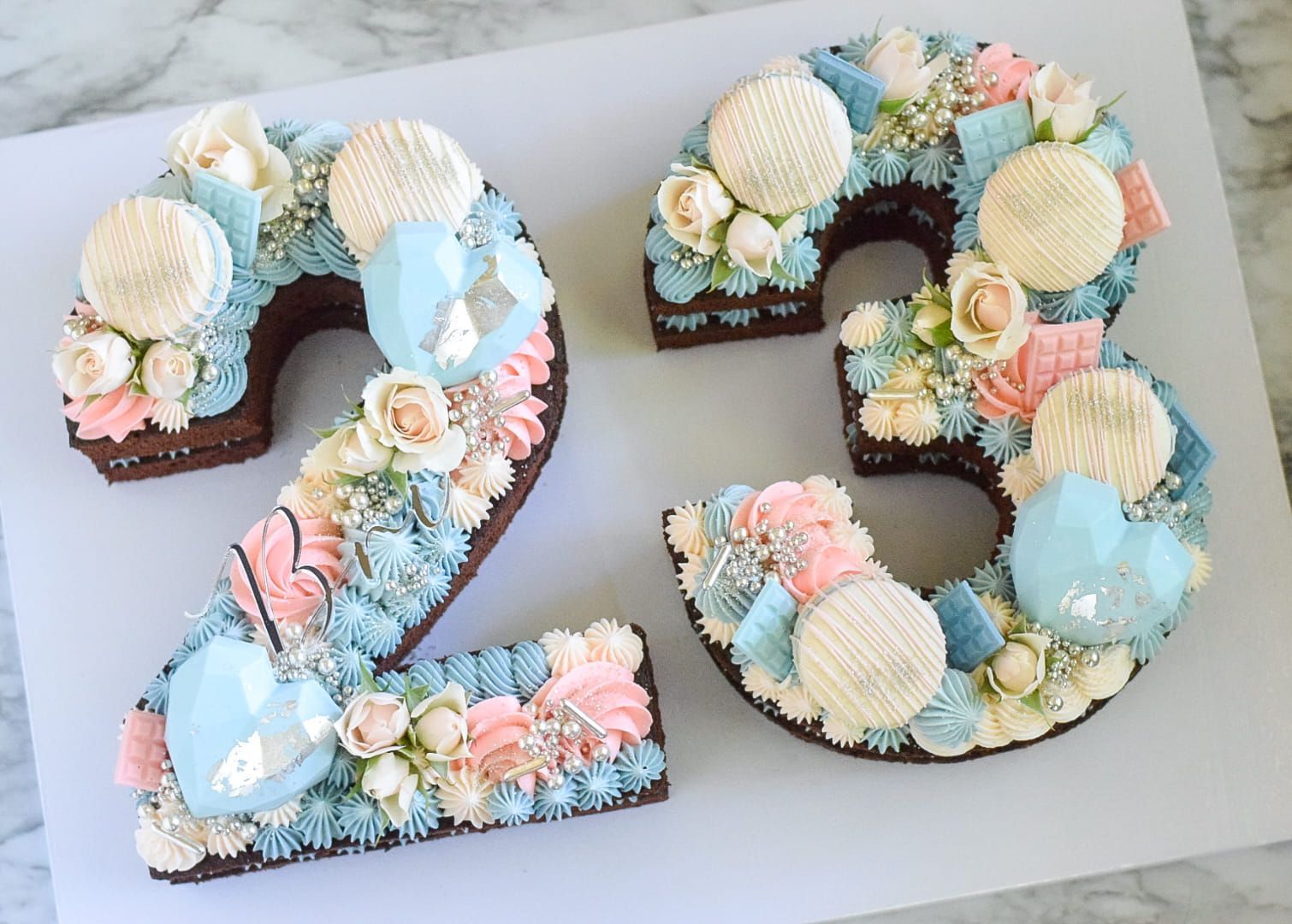 A cake in the shape of the number 23 decorated with flowers.